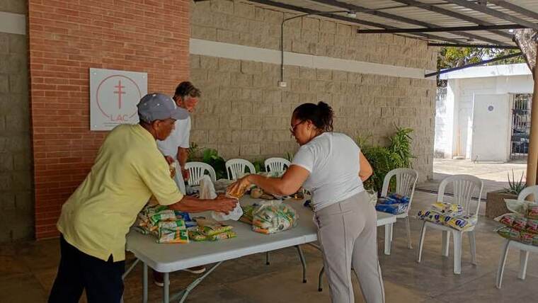 Voluntarios empacando mercados junto al logo de la LAC